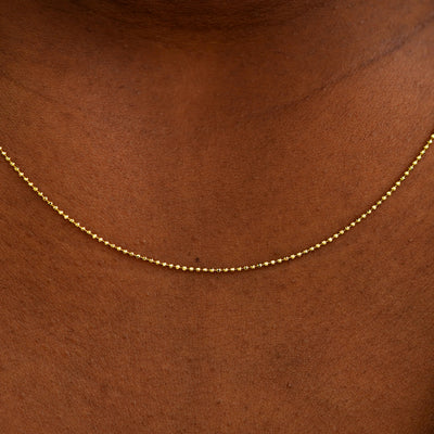Close up view of a model's neck wearing a solid yellow gold Bead Chain