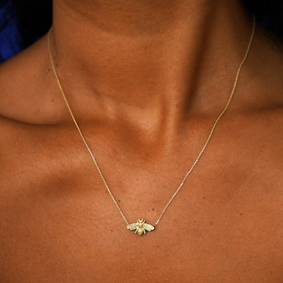 Close up view of a model's neck wearing a solid 14k yellow gold Bee Necklace