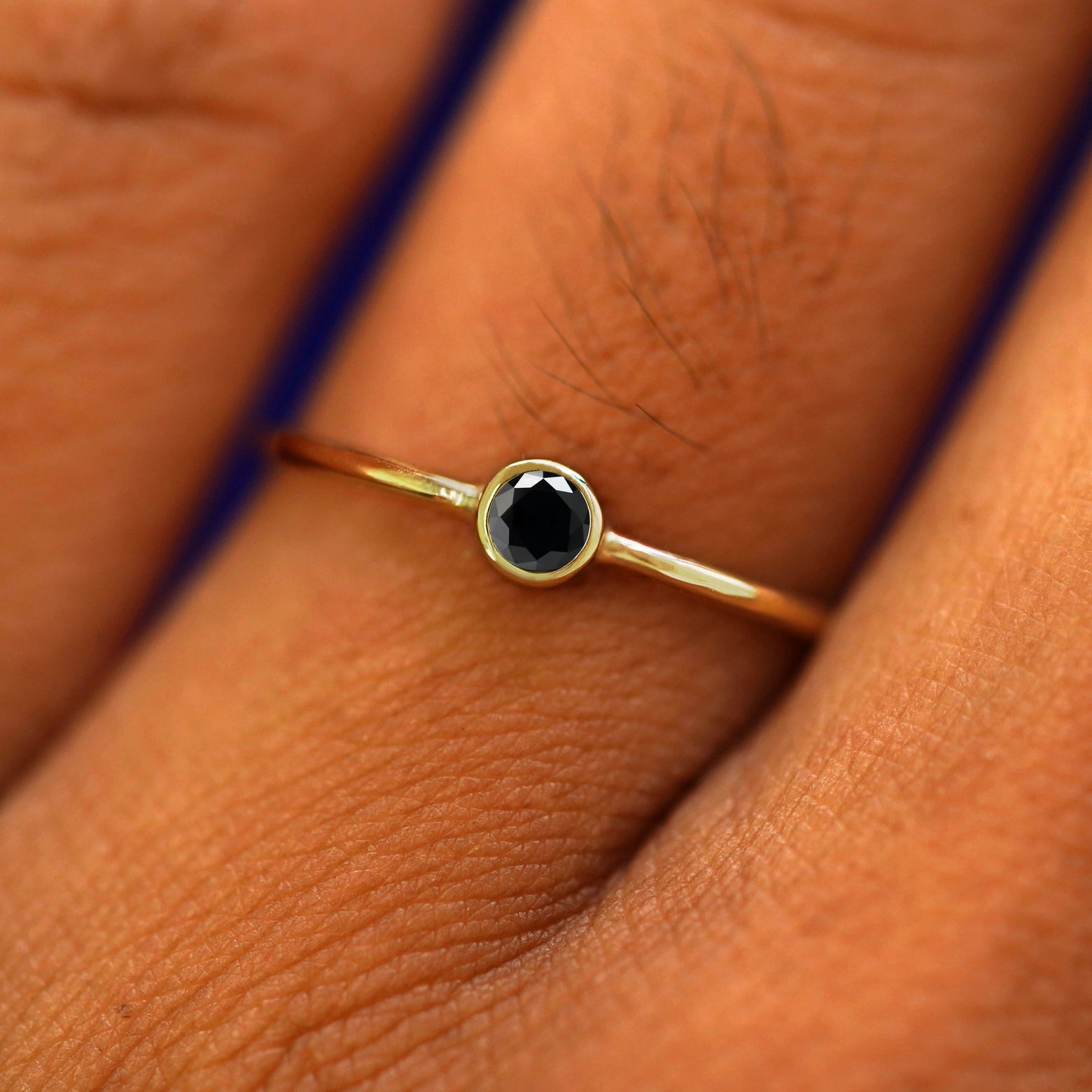 Close up view of a model's fingers wearing a 14k yellow gold Black Diamond Ring