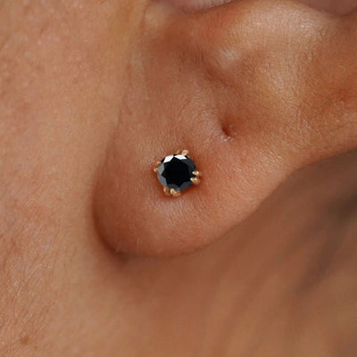 Close up view of a model's ear wearing a 14k yellow gold Onyx Earring