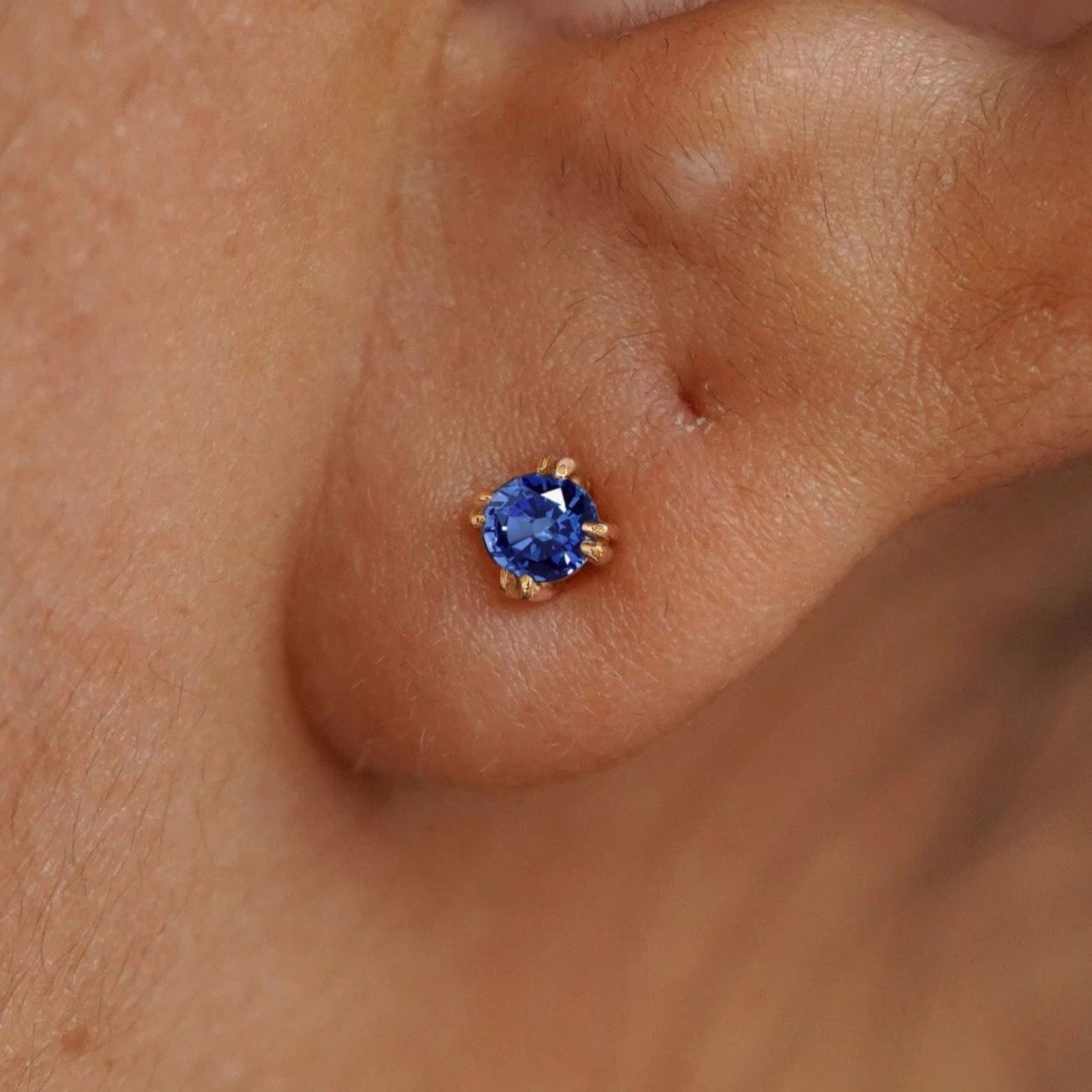 Close up view of a model's ear wearing a 14k yellow gold Sapphire Earring