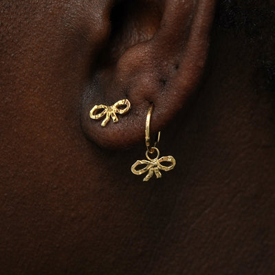 A model wearing a Bow Earring and a Bow Charm on a rope huggie hoop