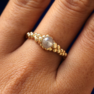 Close up view of a models finger wearing a 14k yellow gold diamond bead fidget bubbles ring