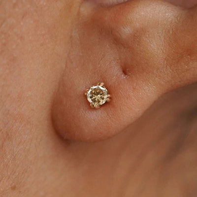 A model's ear wearing a 14k yellow gold Champagne Diamond Earring