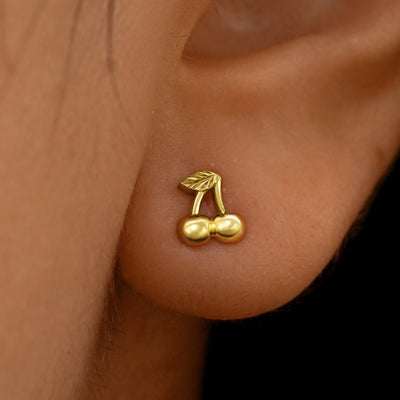 Close up view of a model's ear wearing a 14k yellow gold Cherry Earring