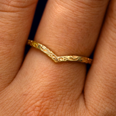 Close up view of a model's fingers wearing a 14k yellow gold Chevron Filigree Band