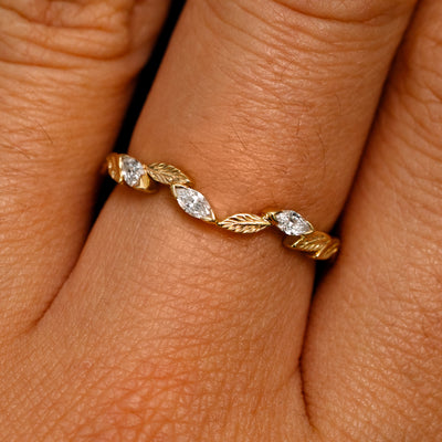 Close up view of a model's fingers wearing a 14k yellow gold Chevron Leaves and Marquise Diamonds Band