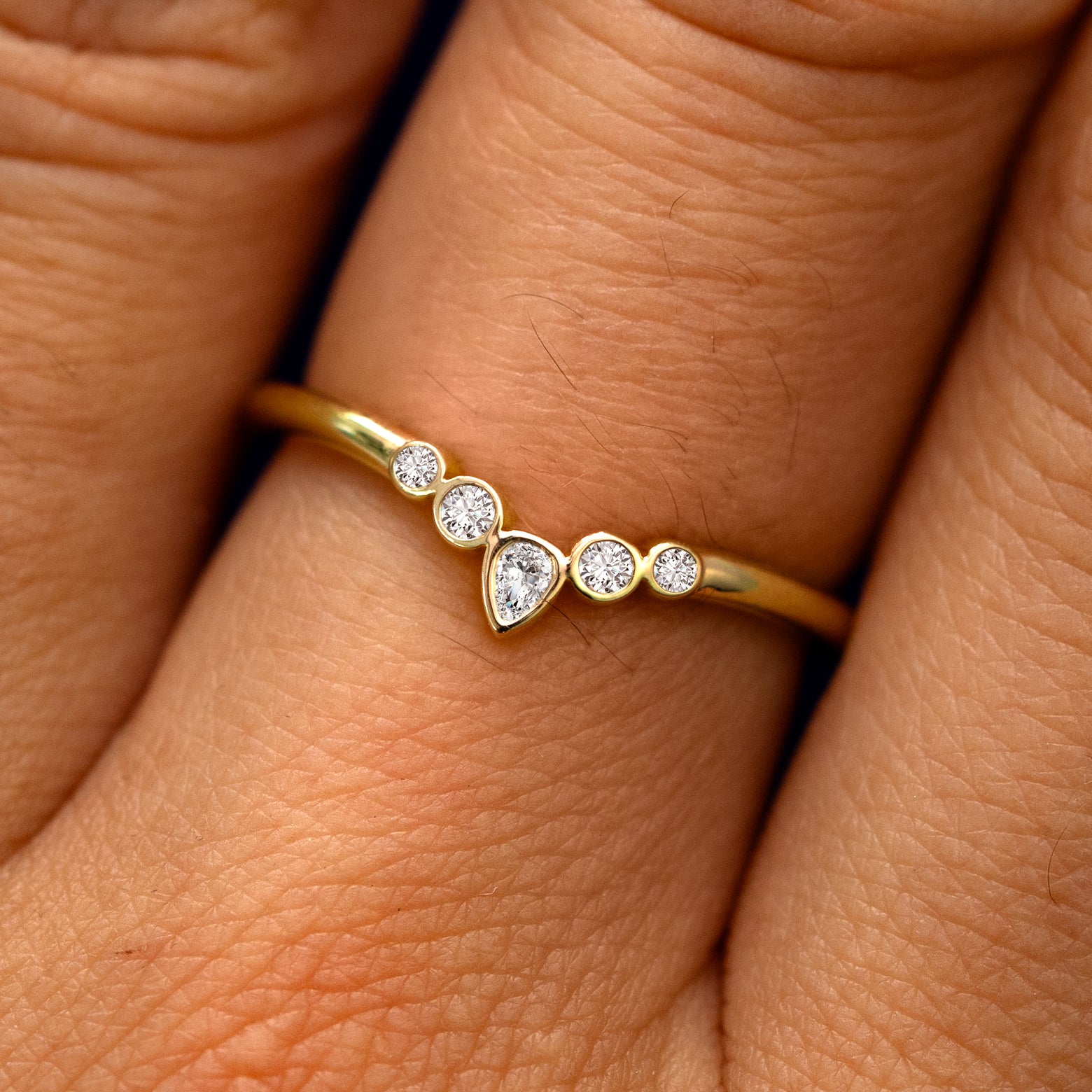 Close up view of a model's fingers wearing a 14k yellow gold Chevron Tiara Diamond Band