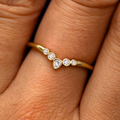 Close up view of a model's fingers wearing a 14k yellow gold Chevron Tiara Diamond Band