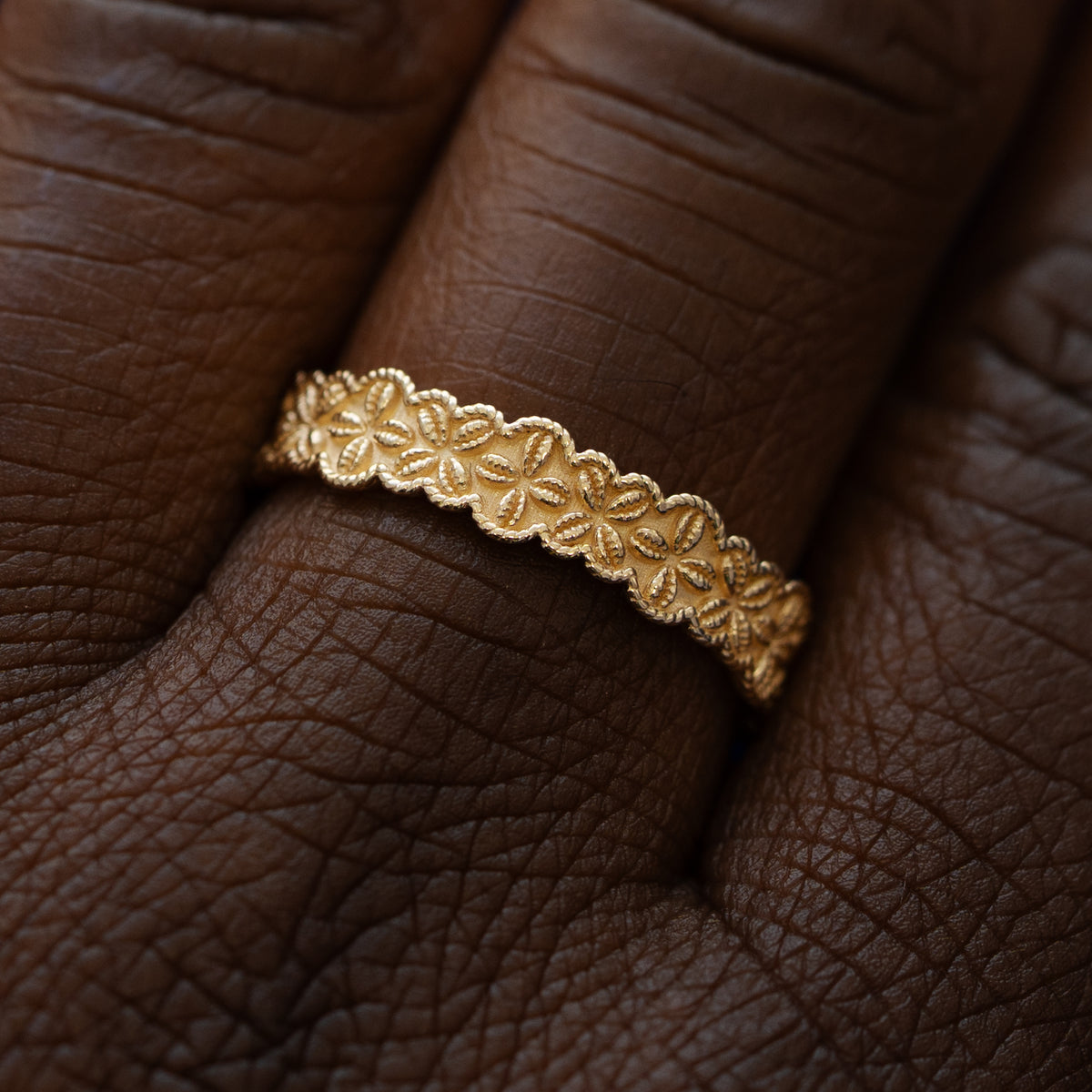 Close up view of a model wearing a solid 14k yellow gold cowrie shell flower and rope band