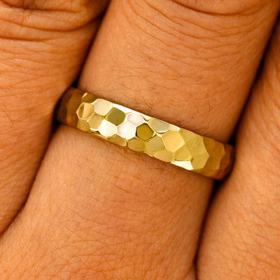 Close up view of a model's fingers wearing a 14k yellow gold Curvy Hammered Band