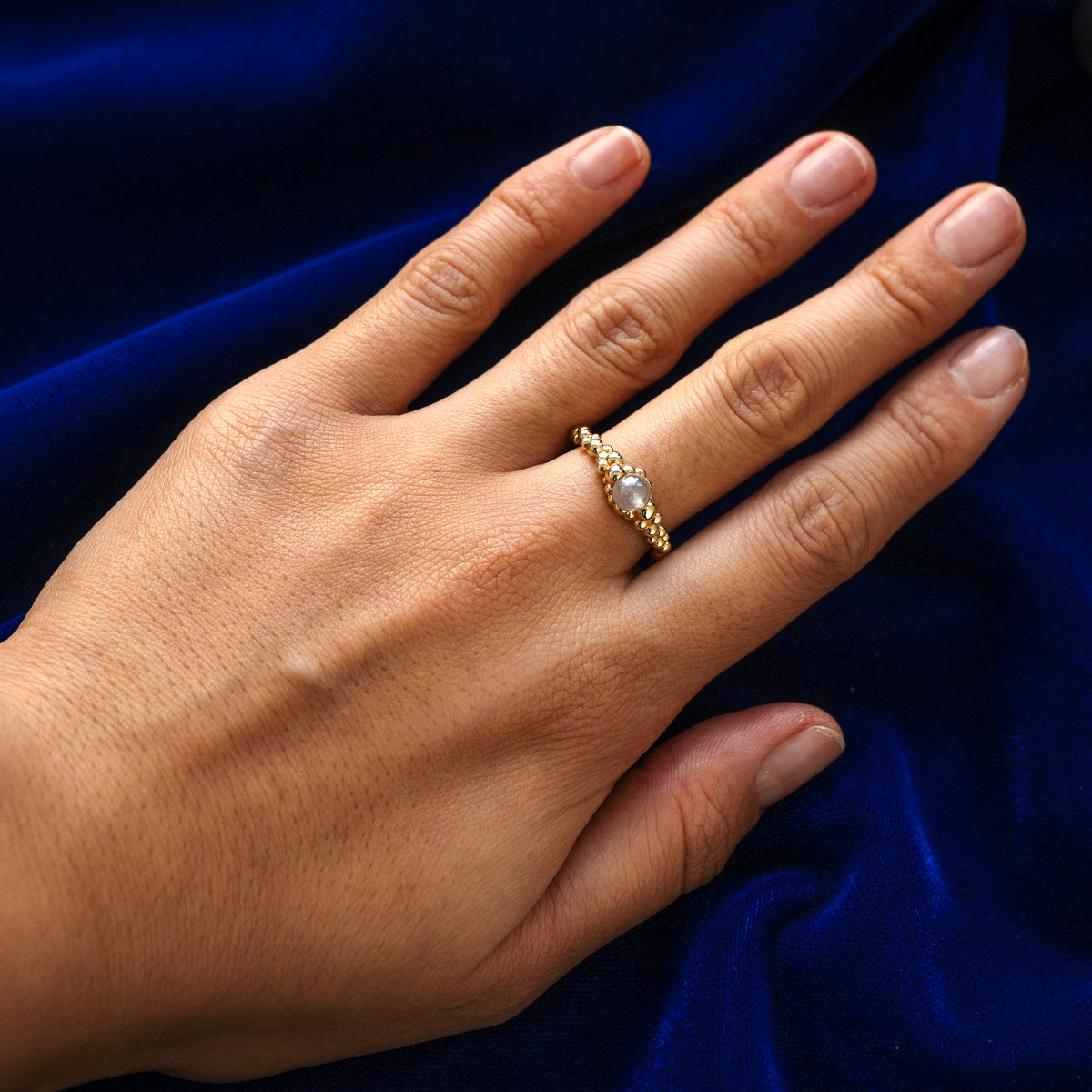 A models finger wearing a 14 karat solid yellow gold diamond bead fidget bubbles ring