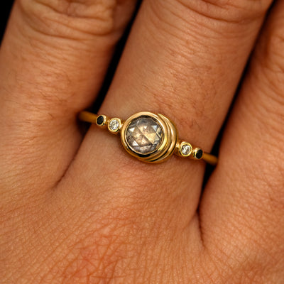 A model's hand wearing a 14k yellow gold Rose Cut Salt and Pepper Diamond Moon Ring