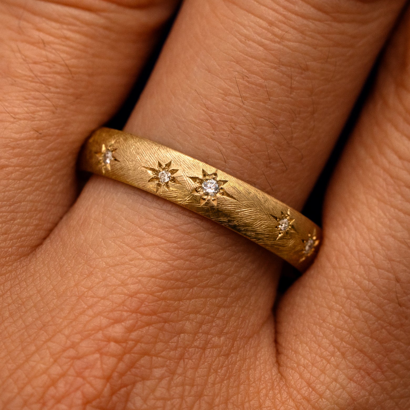 Close up view of a model's fingers wearing a 14k yellow gold Curvy Diamond Stars Velvet Band