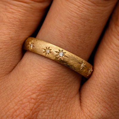 Close up view of a model's fingers wearing a 14k yellow gold Curvy Diamond Stars Velvet Band
