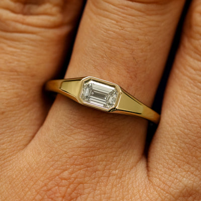 Close up view of a model's fingers wearing a 14k yellow gold Emerald Cut Lab Created Diamond Signet Ring