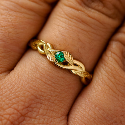 A solid 14k yellow gold emerald leaves and vines ring on a model's finger
