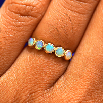 Close up view of a model's hand wearing a yellow gold 5 Gemstones Ring in opal
