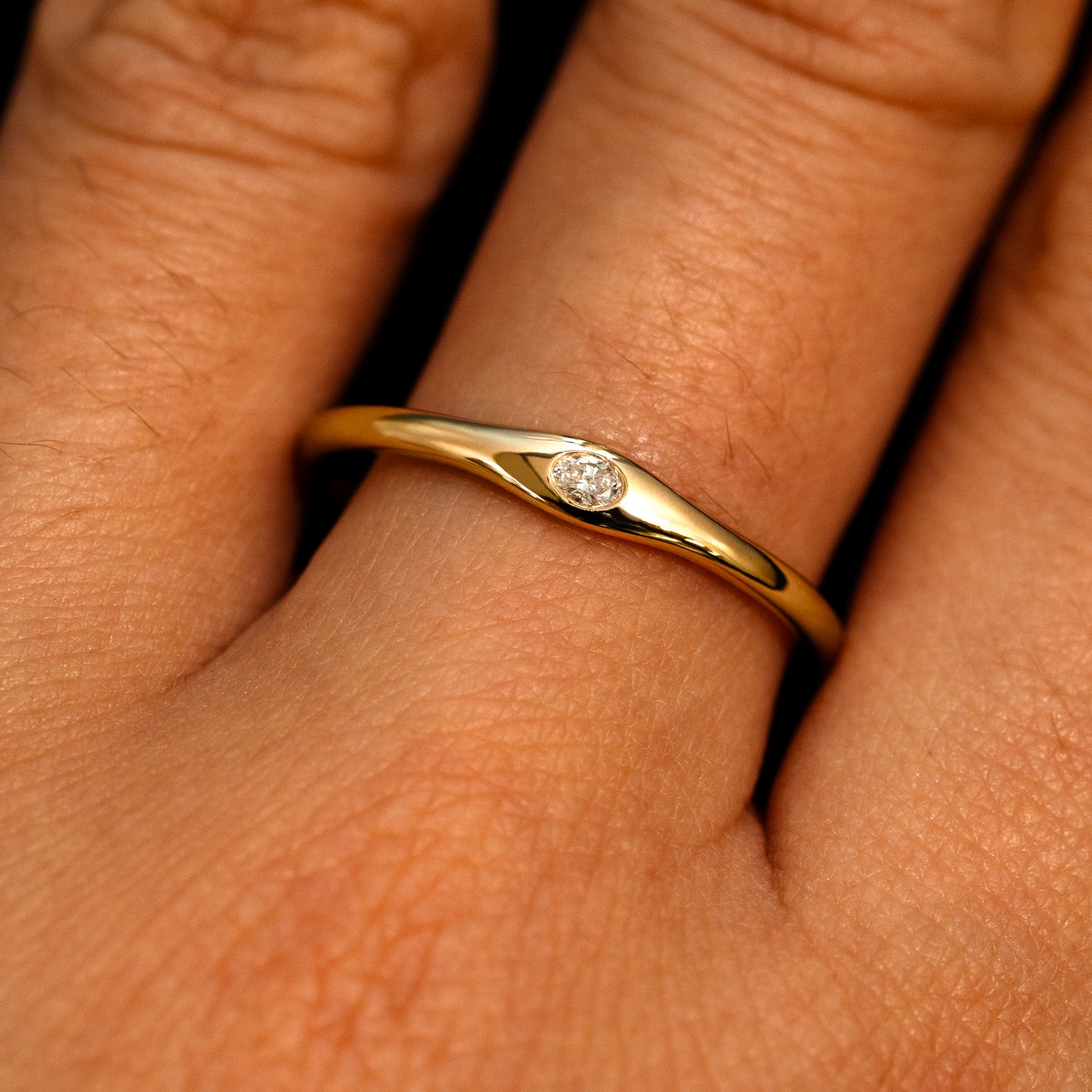 A 14k yellow gold Flush Set Oval Diamond Ring on a model's finger