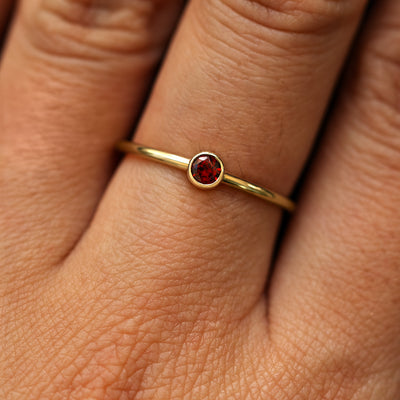 Close up view of a model's fingers wearing a 14k yellow gold Garnet Ring