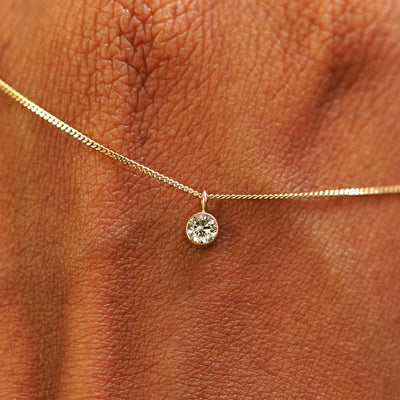Close up view of a 14k yellow gold Champagne Diamond Necklace draped across the back of a model's hand