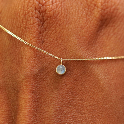 Close up view of a 14k yellow gold Labradorite Necklace draped across the back of a model's hand