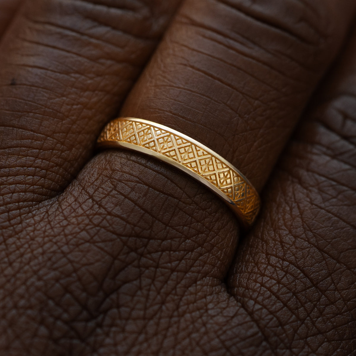 Close up view of a model wearing a solid 14k yellow gold diamond patterned band
