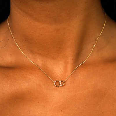 Close up view of a model's neck wearing a solid yellow gold Mini Bound Together Necklace