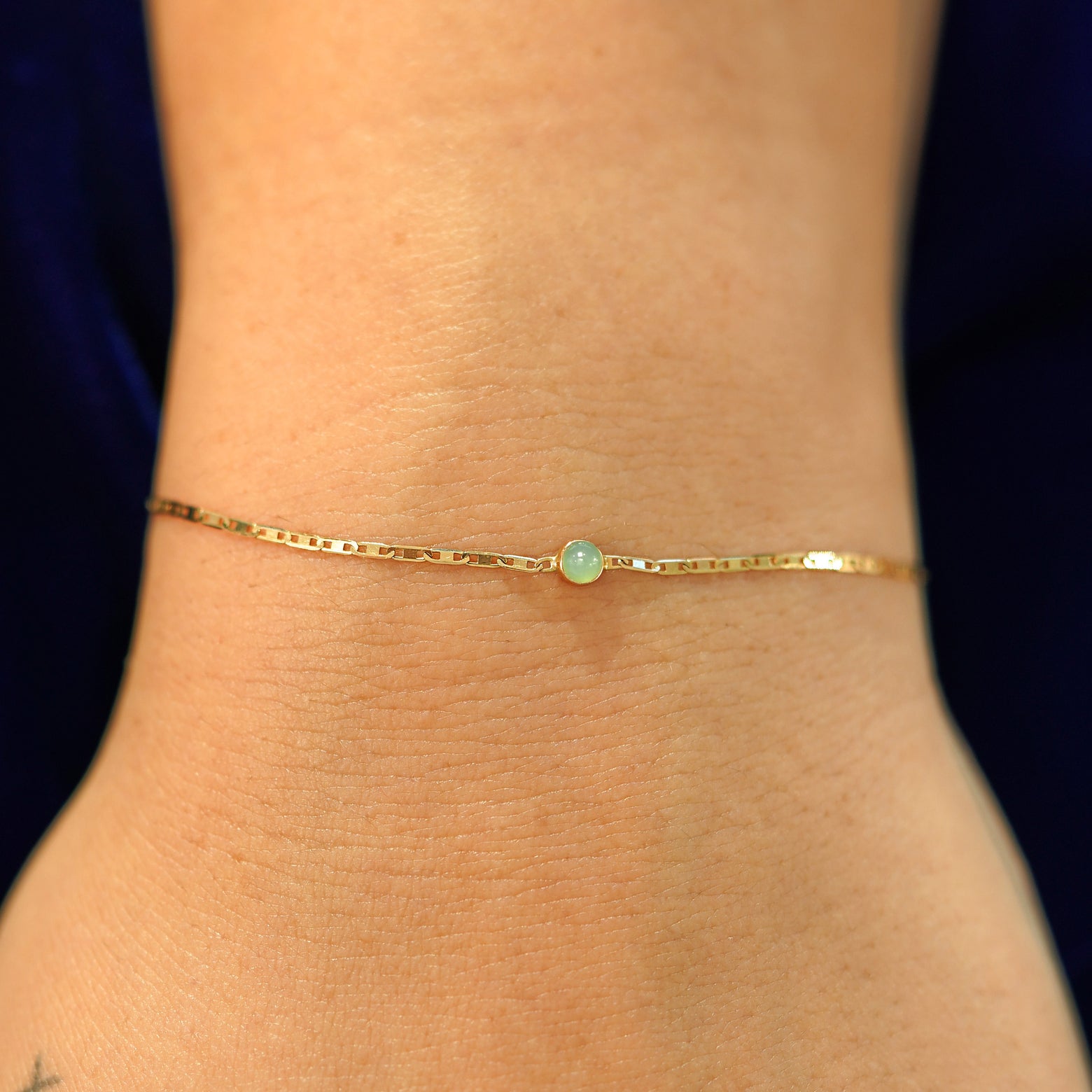 A model's wrist wearing a solid 14k yellow gold Jade Bracelet