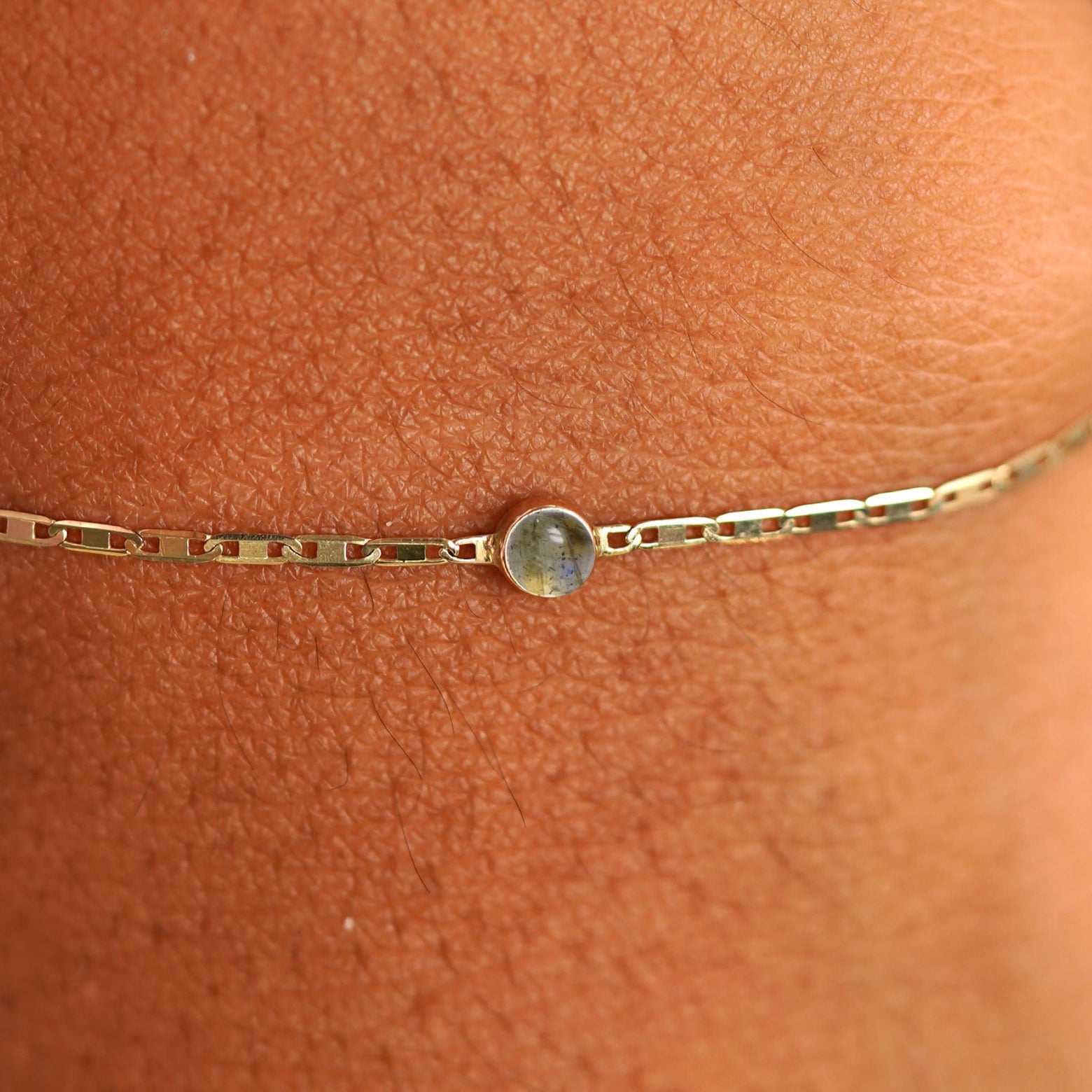 Close up view of a models wrist wearing 14k yellow gold Labradorite Bracelet