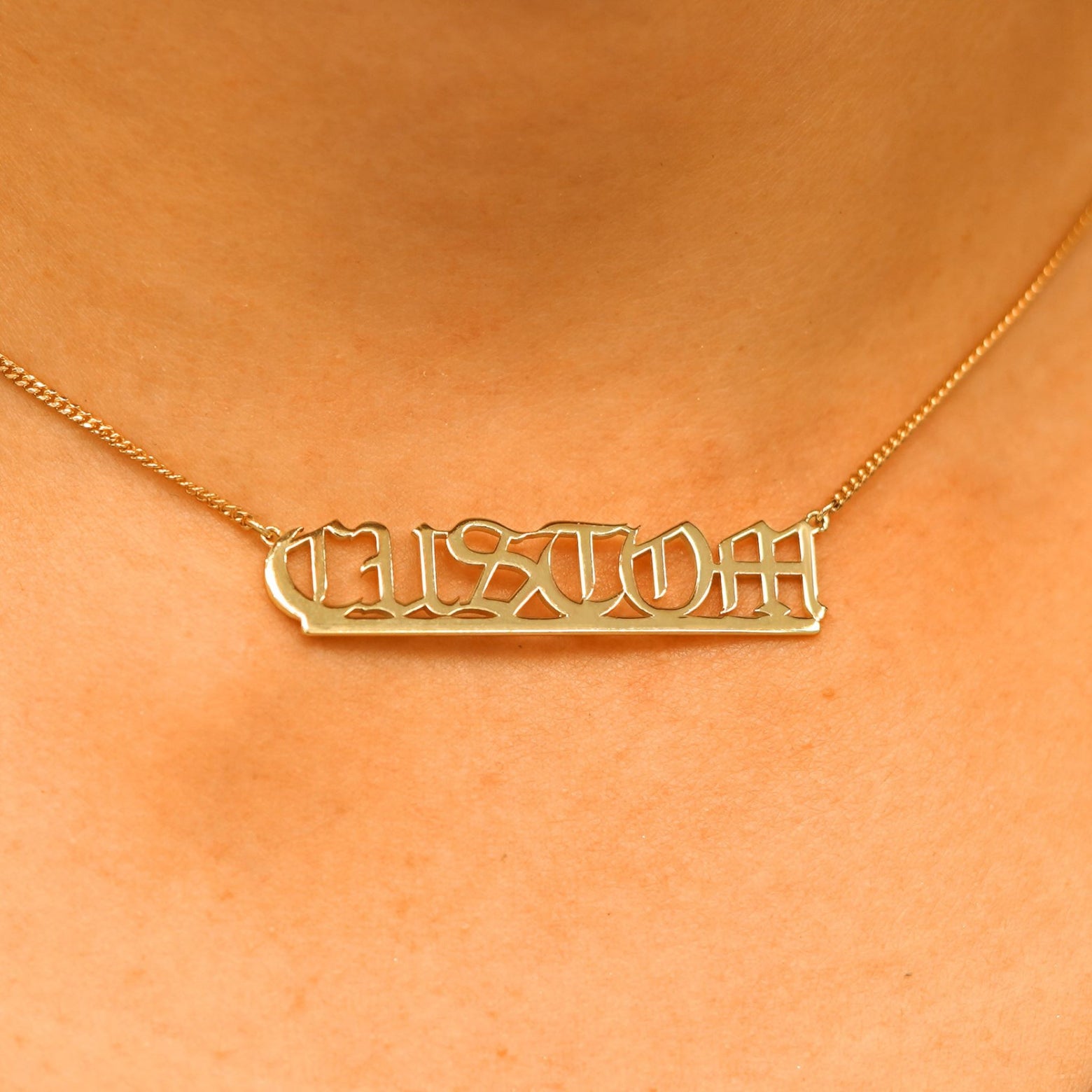 Close up view of a model's neck wearing a Large Custom Nameplate necklace that reads the word Custom