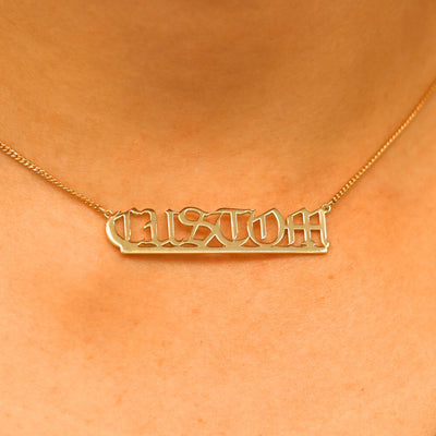 Close up view of a model's neck wearing a Large Custom Nameplate necklace that reads the word Custom