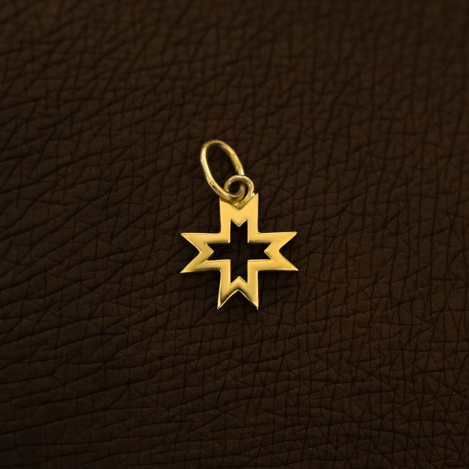 A 14 karat yellow solid gold Large Open 8 Pointed Star Charm on the back of a model's hand