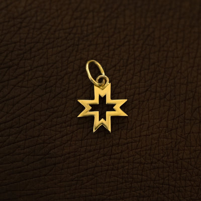 A 14 karat yellow solid gold Large Open 8 Pointed Star Charm on the back of a model's hand