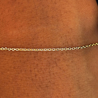 Close up view of a model's wrist wearing a solid 14k yellow gold Medium Cable Chain