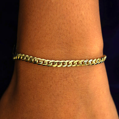 A model's wrist wearing a 14k solid gold Medium Miami Bracelet
