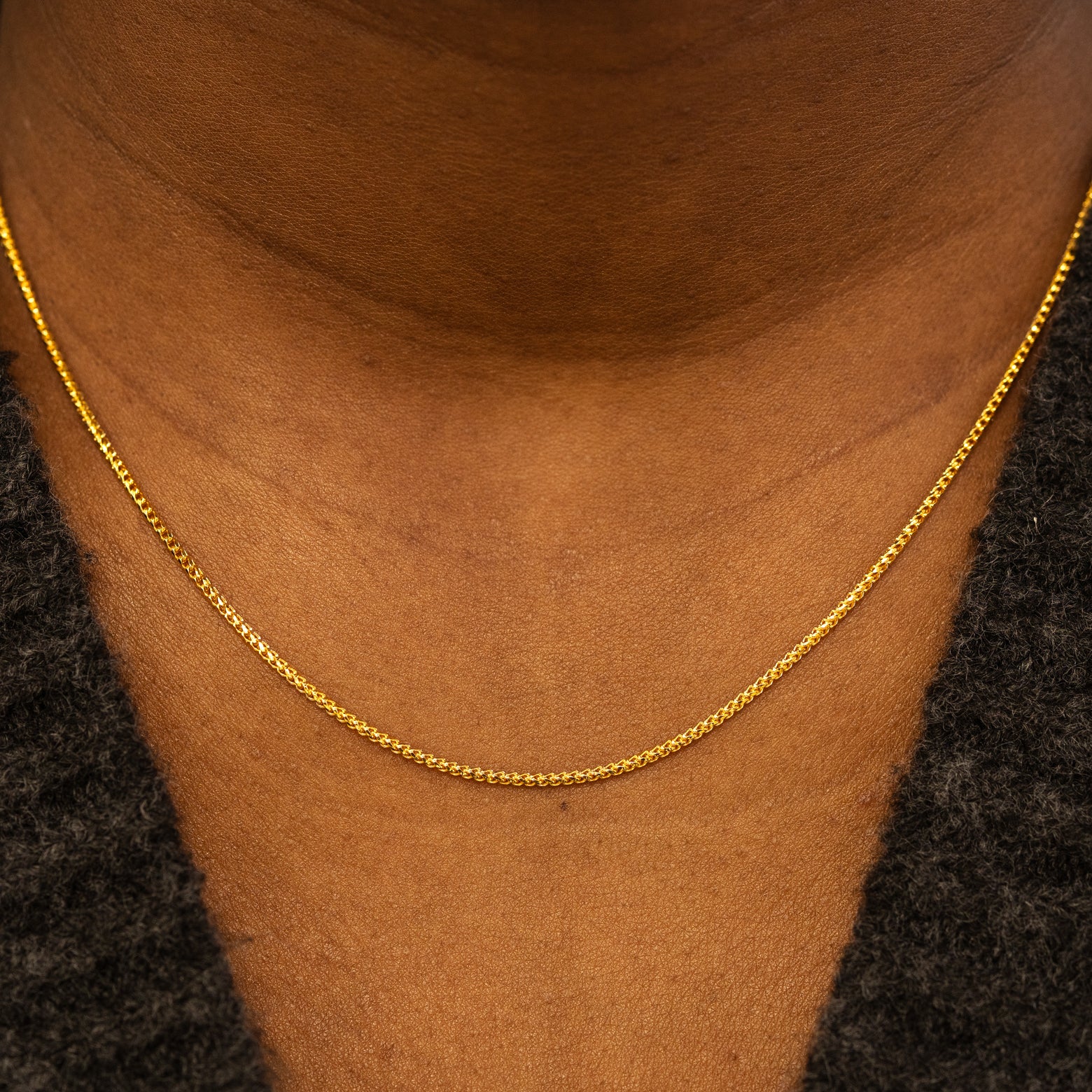 Close up view of a models neck wearing a solid 14k yellow gold Mini Franco Chain Necklace