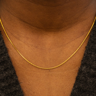 Close up view of a models neck wearing a solid 14k yellow gold Mini Franco Chain Necklace