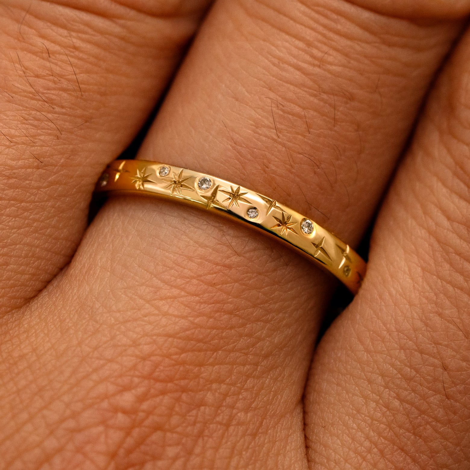 Close up view of a model's fingers wearing a 14k yellow gold Mixed Diamond Stars Band