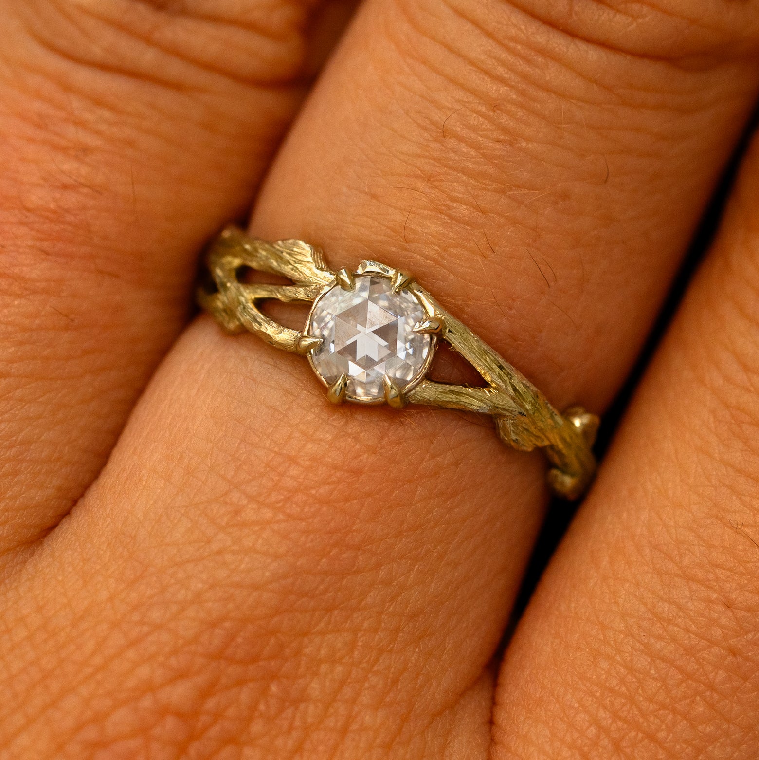 Close up view of a model's fingers wearing a 14k yellow gold Moissanite Branches Ring