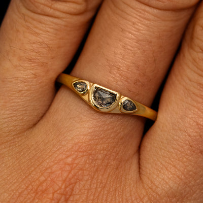 A model's hand wearing a 14k yellow gold Moon Cut Salt and Pepper Diamond Ring