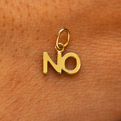 A solid 14k yellow gold No Charm on the back of a models hand