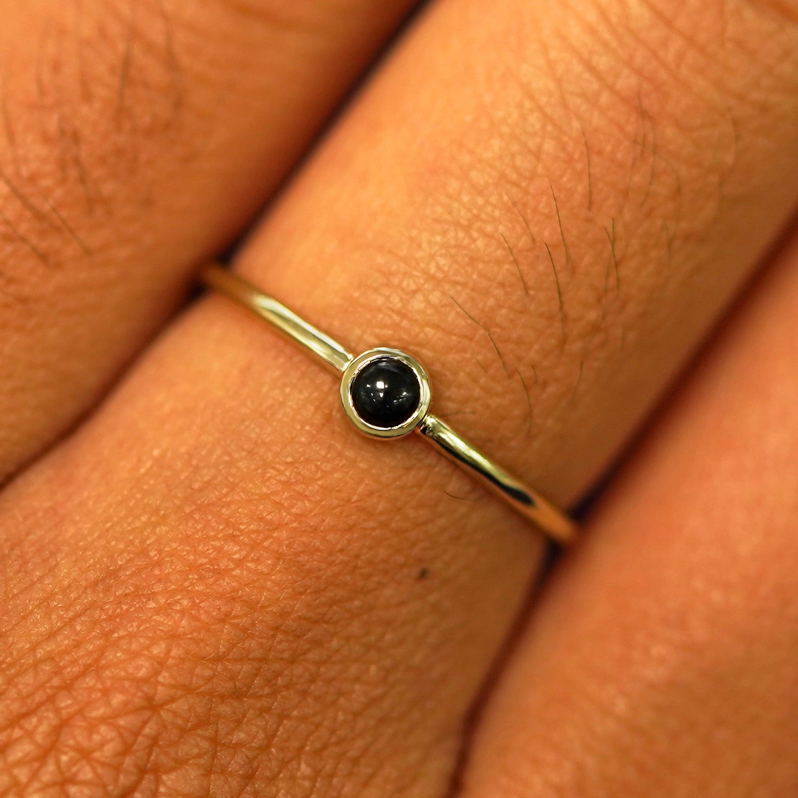 Close up view of a model's fingers wearing a 14k yellow gold Onyx Ring
