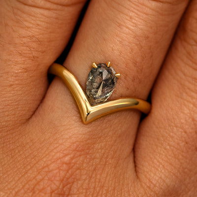 A model's hand wearing a 14k yellow gold Pear Salt and Pepper Diamond Chevron Ring