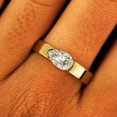 Close up view of a model's fingers wearing a 14k yellow gold Lab Diamond Pear Ring