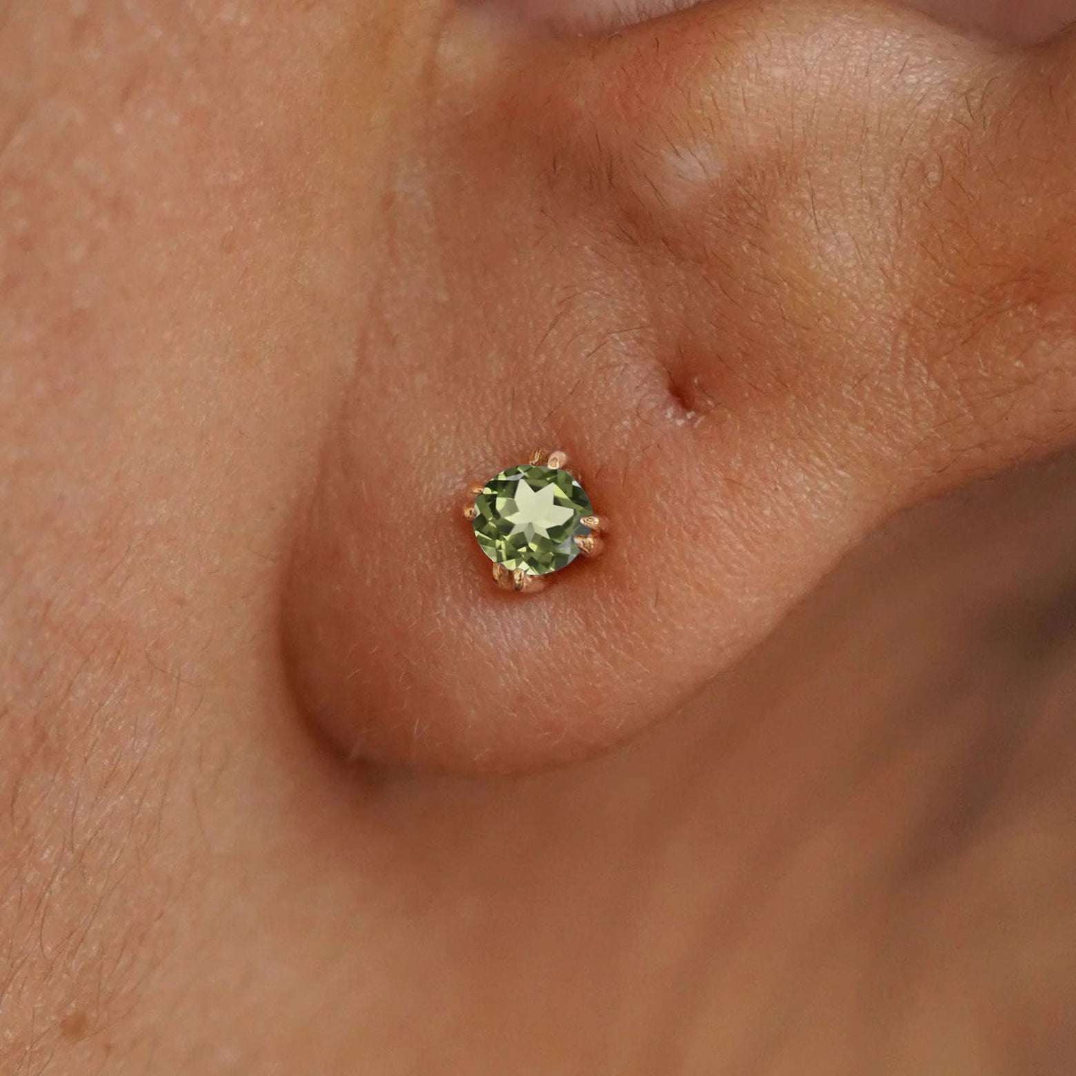 Close up view of a model's ear wearing a 14k yellow gold Peridot Earring