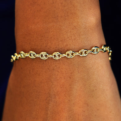 A model's wrist wearing a solid 14k yellow gold Puffy Mariner Bracelet