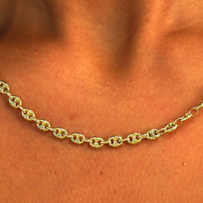 Close up view of a model's neck wearing a solid 14k yellow gold Puffy Mariner Chain