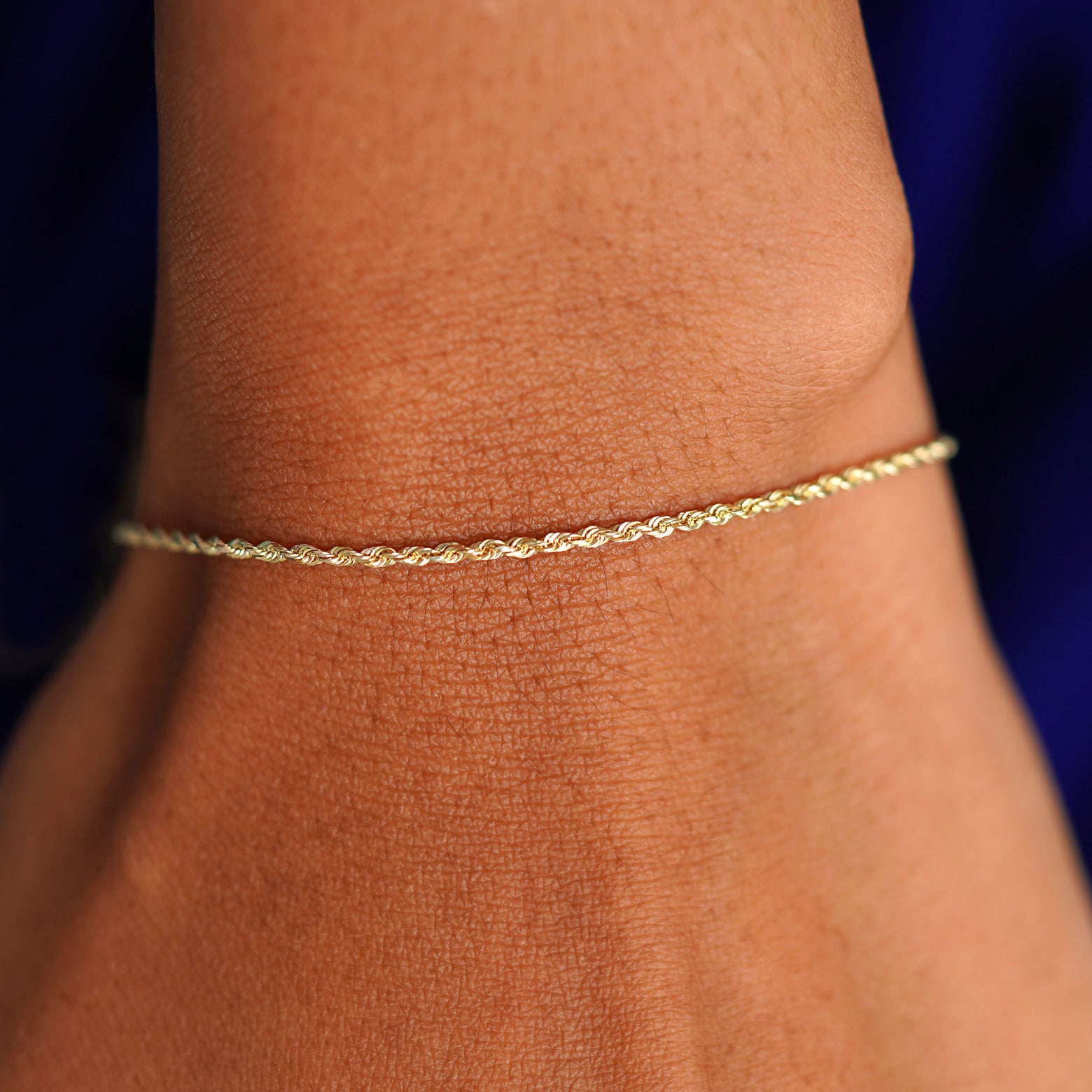 A model's wrist wearing a solid 14k yellow gold Rope Bracelet