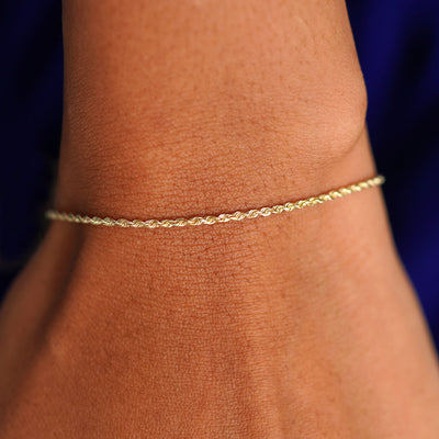 A model's wrist wearing a solid 14k yellow gold Rope Bracelet